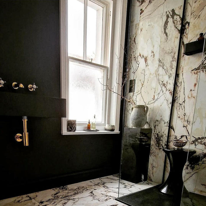 Bathroom interior featuring Maine Capraia Matt Marble 60 × 60cm porcelain wall and floor tiles, styled with bold dark veining against a soft white base, paired with black fixtures and warm brass accents for a striking, contemporary contrast.