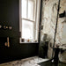 Bathroom interior featuring Maine Capraia Matt Marble 60 × 60cm porcelain wall and floor tiles, styled with bold dark veining against a soft white base, paired with black fixtures and warm brass accents for a striking, contemporary contrast.