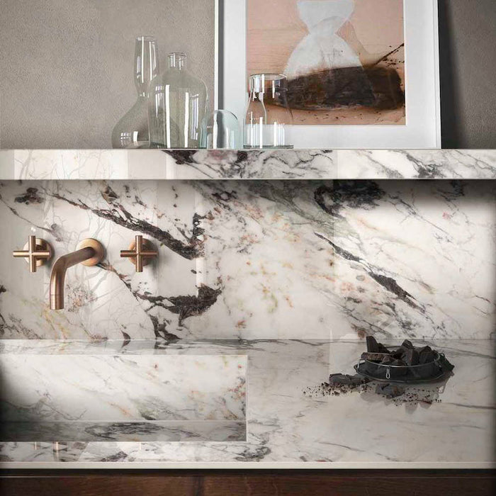 Bathroom vanity featuring Maine Capraia Matt Marble 60 × 60cm porcelain wall and basin tiles, showcasing a soft white base with bold, expressive veining, paired with brushed brass fittings and warm wood accents for a refined, contemporary finish.
