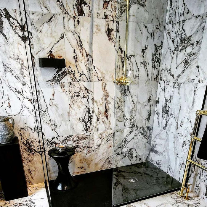 Shower enclosure featuring Maine Capraia Matt Marble 60 × 60cm porcelain wall tiles, showcasing a striking white base with bold, expressive veining in deep grey and warm undertones, paired with black accents and brass fittings for a dramatic, design-led finish.