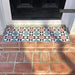 Outdoor doorstep featuring Maison MINI Fern 15cm x 15cm Victorian style tiles, showcasing a geometric star pattern in soft green, pink, black and white, paired with traditional red brickwork and a black front door.