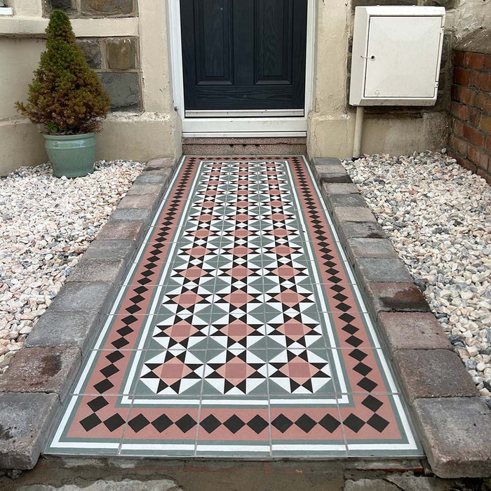 Maison Mini Fern 15cm x 15cm Victorian style tiles, featuring an intricate geometric pattern in soft green, terracotta, black and white across a statement front garden path with coordinating decorative borders.