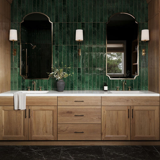 Bathroom vanity featuring Maldives Pine Green 5 × 40cm gloss ceramic wall tiles, laid vertically with rich green tonal variation, paired with wooden cabinetry, twin basins, brass fittings, and framed mirrors for a refined, design-led finish.