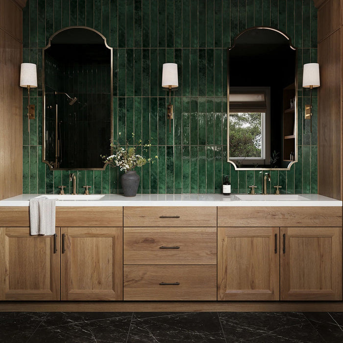 Bathroom vanity featuring Maldives Pine Green 5 × 40cm gloss ceramic wall tiles, laid vertically with rich green tonal variation, paired with wooden cabinetry, twin basins, brass fittings, and framed mirrors for a refined, design-led finish.