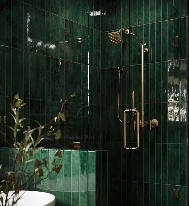 Walk-in shower featuring Maldives Pine Green 5 × 40cm gloss ceramic wall tiles, laid vertically with rich green tonal variation, paired with brass shower fittings, glass enclosure, and a built-in tiled bench for a cohesive finish.