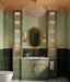 Bathroom interior featuring Maldives Pine Green 5 × 40cm gloss ceramic wall tiles, laid vertically across the lower half of the wall with rich green tonal variation, paired with a sage vanity unit, brass fittings, patterned floor tiles, and a decorative mirror for a layered, characterful finish.