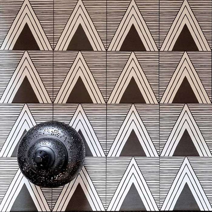 Alhambra Pyramid 20x20cm Moroccan tiles displayed in a bold black and white triangular pattern, styled with a decorative black lantern accent for a modern geometric marketing setup.