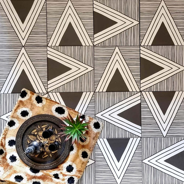 Alhambra Pyramid 20x20cm Moroccan tiles arranged in a striking black and white triangular pattern, styled with a patterned cushion, a decorative tray, and a small succulent plant for a modern Moroccan-inspired display.