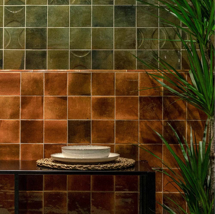 Interior featuring Beijing Amber Square 10x10cm Moroccan-style ceramic wall tiles, styled with dark furniture, neutral ceramics and green foliage for a warm, earthy look.
