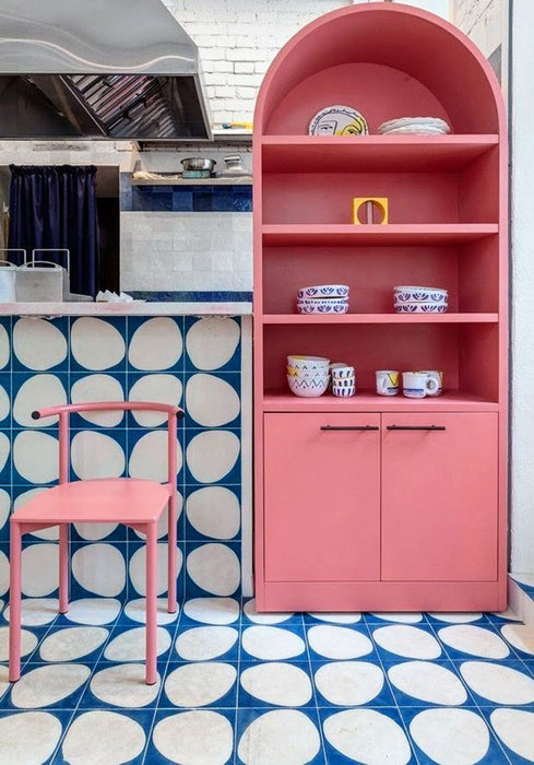 Kitchen interior featuring Pebble Beach Blue 20 x 20cm patterned tiles, used across the floor and bar front to create a bold geometric statement in rich blue and soft neutral tones, complemented by playful pink cabinetry and contemporary styling for a vibrant, design-led space.