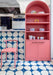 Kitchen interior featuring Pebble Beach Blue 20 x 20cm patterned tiles, used across the floor and bar front to create a bold geometric statement in rich blue and soft neutral tones, complemented by playful pink cabinetry and contemporary styling for a vibrant, design-led space.