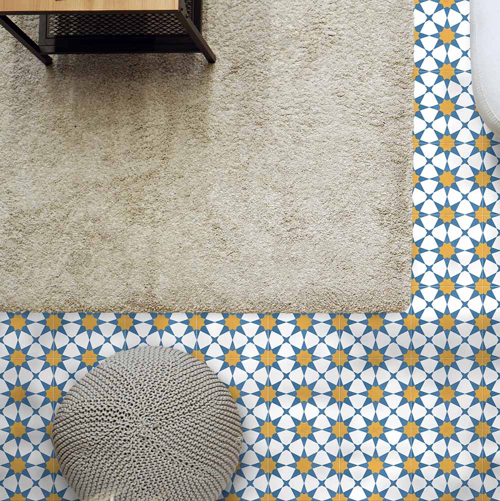 Living room featuring Agraba Sunshine 20x20cm Moroccan-style ceramic floor tiles with a geometric star pattern in blue, mustard, and white tones, styled with a neutral rug and textured pouffe for a warm Mediterranean look.