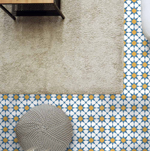 Living room featuring Agraba Sunshine 20x20cm Moroccan-style ceramic floor tiles with a geometric star pattern in blue, mustard, and white tones, styled with a neutral rug and textured pouffe for a warm Mediterranean look.