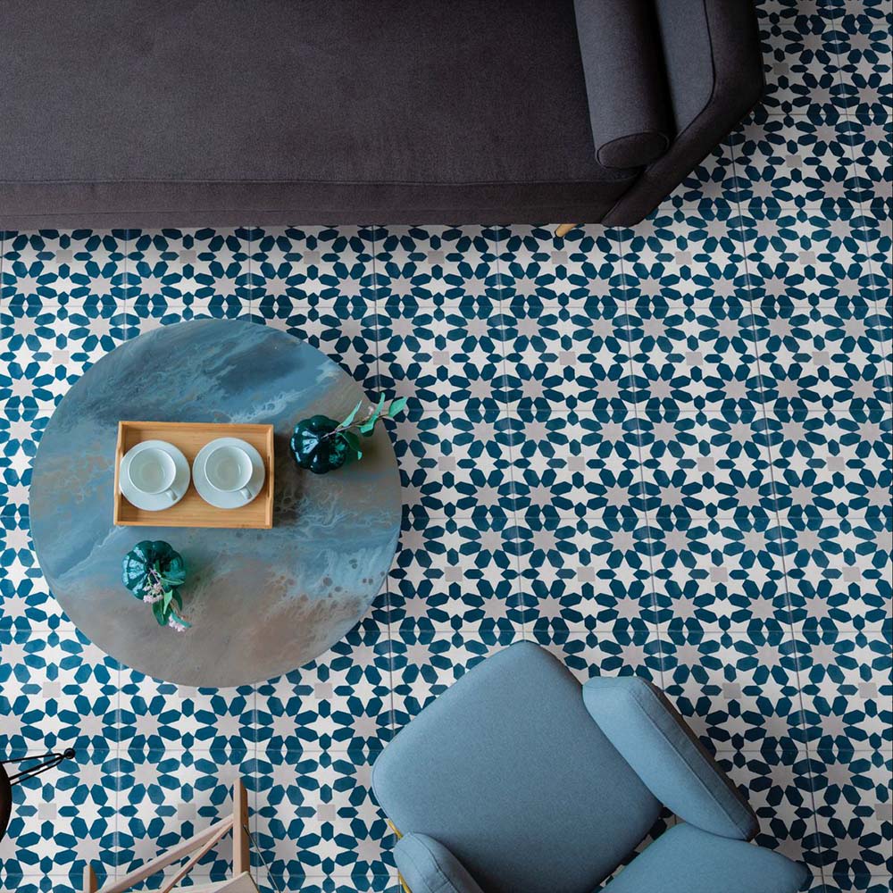 Marketing setting featuring Soukaina Blue C Moroccan-style 20cm x 20cm patterned porcelain floor tiles, showcasing an all-over geometric star pattern in rich blue and white tones with a matt finish, styled in a contemporary living space.