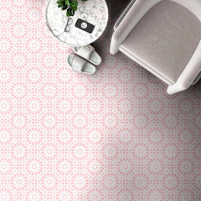 Overhead interior view featuring Fizaan Pink Rose 20x20cm Moroccan-style porcelain floor tiles, showcasing a delicate geometric pattern in soft pink and white tones, styled with a modern armchair and side table.