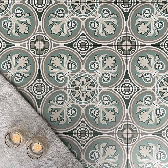 Overhead view of Europa Toulouse 20x20cm Victorian Moroccan style floor tiles in green, grey and cream tones, forming a decorative repeating pattern, styled with a soft grey rug and candles in a cosy interior setting.