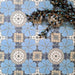 Bloom Azul Blue 20x20cm Moroccan-style ceramic tiles in a marketing flat-lay setting, featuring decorative floral patterns in soft blue, white, grey, and beige tones, styled with blue botanical accents for contrast.