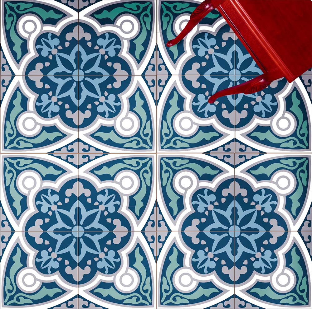 Overhead view of Europa Bucharest 20x20cm Victorian Moroccan style floor tiles in blue, teal and white tones, forming an ornate geometric pattern, styled with a red chair leg in a decorative interior setting.