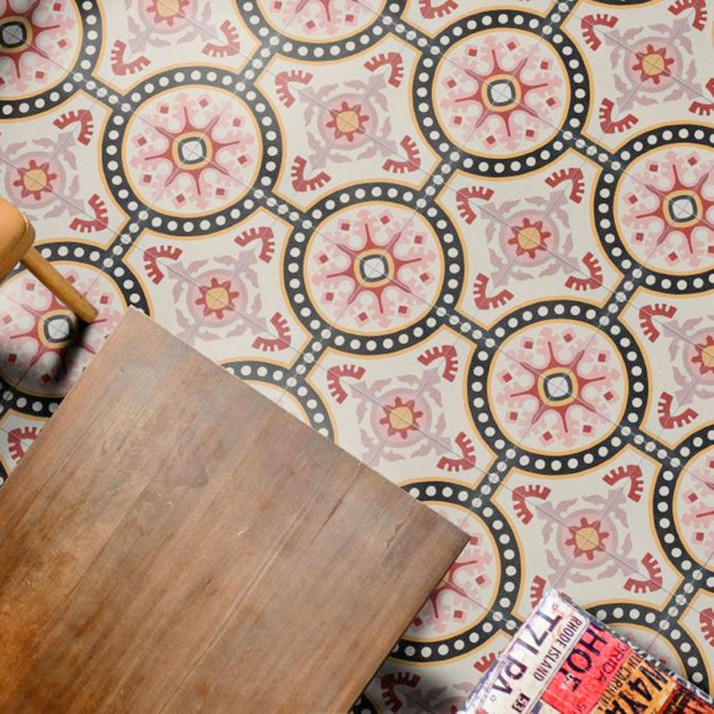 Overhead view of Europa Dortmund 20x20cm Victorian Moroccan style floor tiles in red, cream, grey and black tones, forming a decorative repeating pattern, styled with wooden furniture and magazines in an interior setting.