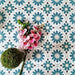Flatlay featuring Clarence House Teal Green 20x20cm Victorian Moroccan-style porcelain tiles, styled with pink orchids and green foliage to highlight the bold teal and white geometric pattern.