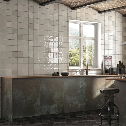 Marketing setting featuring Zellij White Gloss Square Moroccan-style tiles in a 13.2cm x 13.2cm format, with a glossy white glaze and subtle handmade texture, styled on kitchen walls alongside industrial cabinetry and rustic ceiling beams.