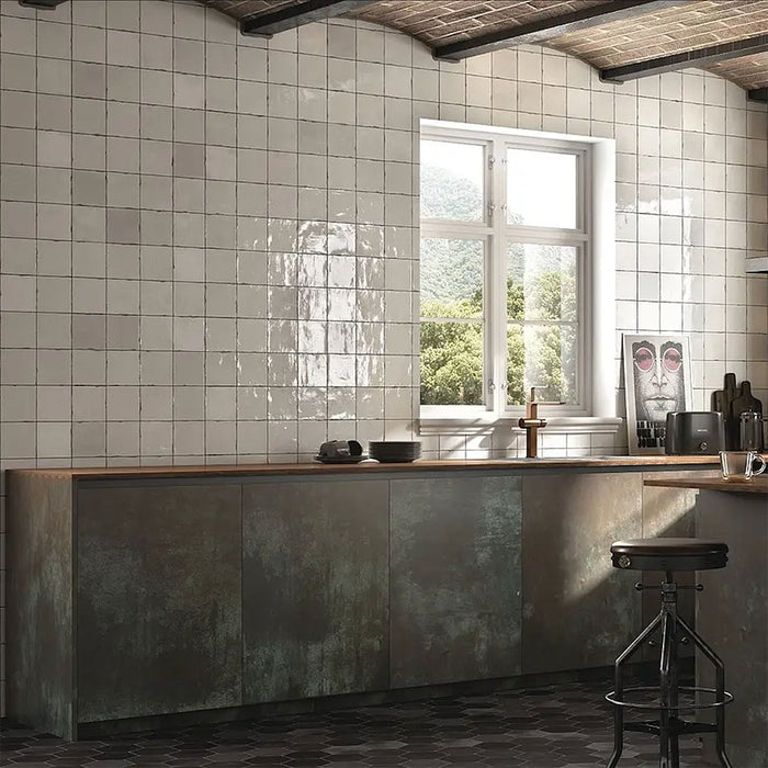 Marketing setting featuring Zellij White Gloss Square Moroccan-style tiles in a 13.2cm x 13.2cm format, with a glossy white glaze and subtle handmade texture, styled on kitchen walls alongside industrial cabinetry and rustic ceiling beams.