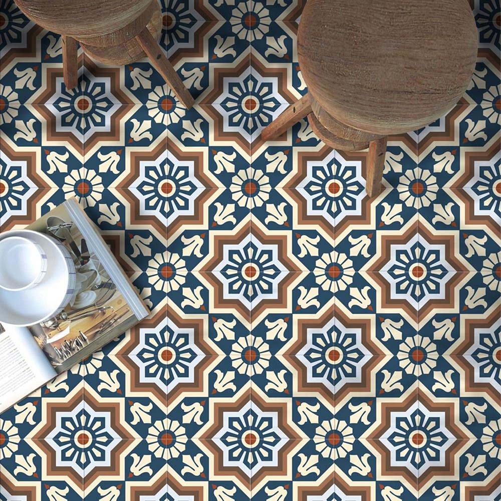 Brompton Grand 20x20cm Victorian-Moroccan-style ceramic floor tiles in a marketing setting, featuring intricate star and floral patterns in navy blue, white, and terracotta tones, styled with wooden stools and an open magazine on the floor.