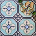 Overhead view of Europa Gothenberg 20x20cm Victorian Moroccan style floor tiles in blue, mint green and cream tones, forming a geometric pattern, styled with decorative shoes and small plants.