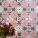 Bloom Rose Pink 20x20cm Moroccan-style ceramic tiles in a marketing flat-lay setting, featuring decorative floral patterns in soft pink, white, and taupe tones, styled with pink flowers for a coordinated look.