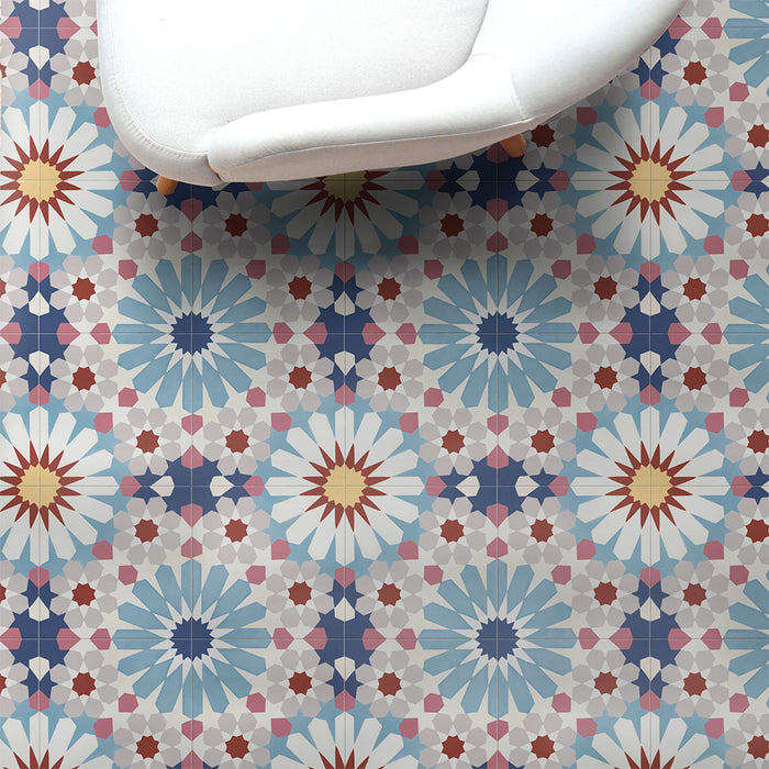 Interior setting featuring Fizaan Fiera 20x20cm Moroccan-style porcelain floor tiles, showcasing a bold geometric pattern in soft blue, red and neutral tones, styled with a modern white chair.