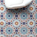 Interior setting featuring Fizaan Fiera 20x20cm Moroccan-style porcelain floor tiles, showcasing a bold geometric pattern in soft blue, red and neutral tones, styled with a modern white chair.