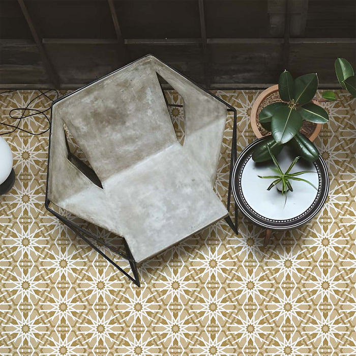 Maroush Mareshan Vintage Gold 18.7x21.6cm Moroccan hexagonal tiles with intricate white star patterns, styled in a modern interior with a concrete chair, potted plants, and warm golden tones for an artisan-inspired look.