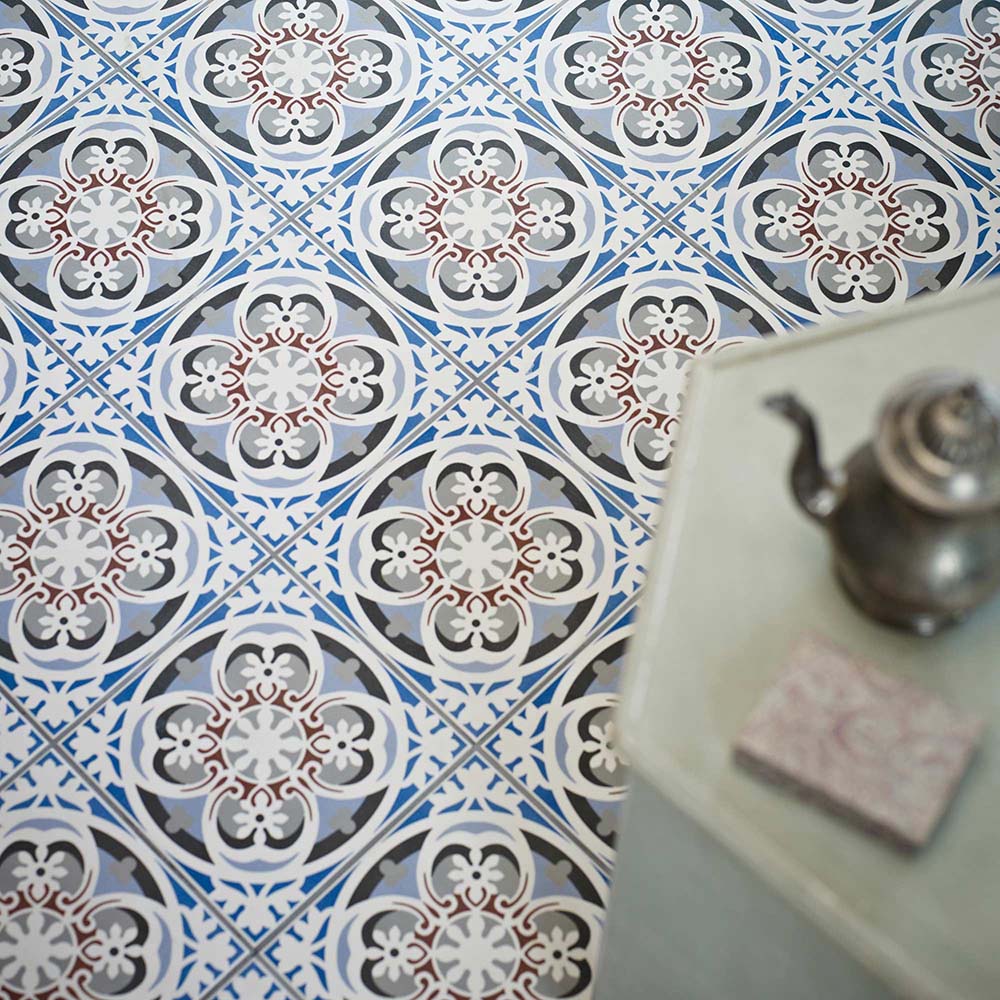 Empire Blue 15x15cm Victorian-style floor tiles in a marketing setting, featuring intricate floral and geometric motifs in blue, grey, white, and terracotta tones for a classic heritage look.