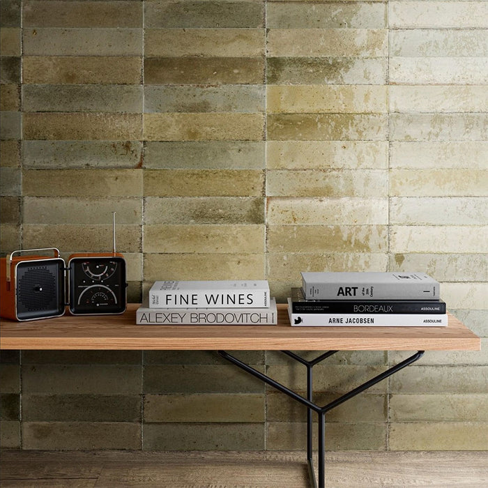 Interior styled with Izmir Brick Sage Green Gloss 6x25cm ceramic wall tiles, featuring a wooden console table with design books and a retro radio, creating a warm, modern look with natural texture.