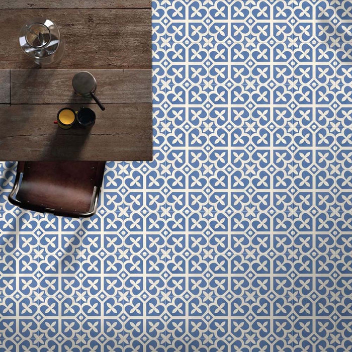 Marketing setting featuring Iris Blue Victorian Moroccan-style 20×20cm porcelain floor tiles, showcasing the repeating blue and cream geometric pattern styled with rustic wooden furniture for a lifestyle-led interior scene.