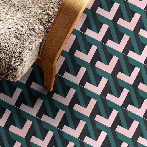 Living room setting featuring Geometry Lagoon 20x20cm patterned ceramic floor tiles, showcasing an interlocking geometric design in teal, blush pink, and charcoal tones, styled with a wooden chair and textured cushion.
