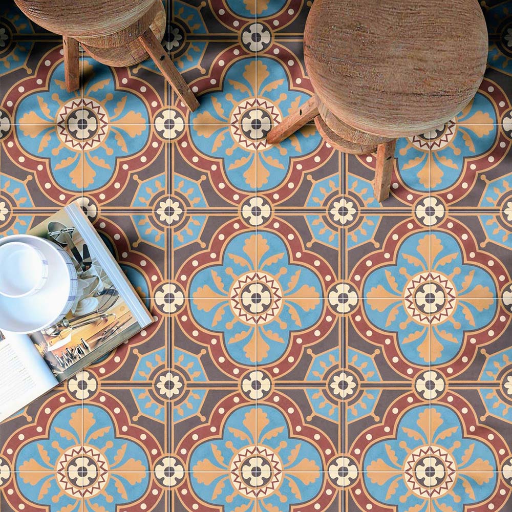 Overhead view of Europa Hanover 20x20cm Victorian Moroccan style floor tiles in blue, terracotta and cream tones, forming an intricate decorative pattern, styled with wooden stools and a tray with magazines and crockery.