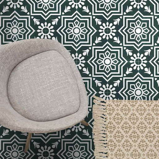 Brompton Victorian Green 20x20cm geometric patterned ceramic tiles in a marketing setting, featuring a white star and floral design on a deep green background, styled with a grey upholstered chair and beige patterned rug.