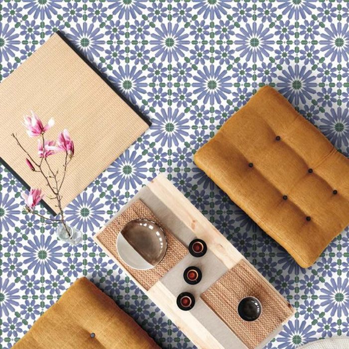Overhead interior setting featuring Fizaan Ocean 20x20cm Moroccan-style porcelain floor tiles, showcasing a repeating geometric pattern in blue, green and white tones, styled with warm wooden furniture and soft furnishings.