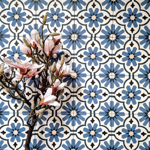 Flatlay featuring Clarence House Azul Blue 20x20cm Victorian Moroccan-style porcelain tiles, styled with pink magnolia flowers to highlight the intricate blue and white geometric pattern.