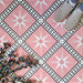 Galata Pink Moroccan Style 20x20cm tiles used in a styled setting, featuring a geometric star pattern in soft pink, white, and black with a matt finish, paired with neutral shoes and decorative foliage.