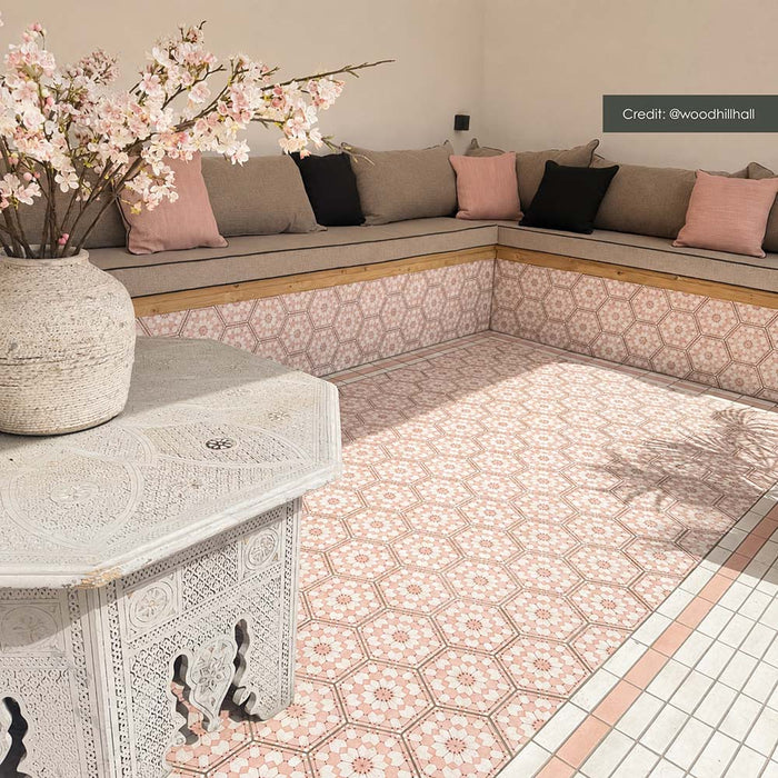 Outdoor seating area featuring Maroush Dusty Pink 18.7cm x 21.6cm Moroccan style hexagon tiles across the floor and built-in seating, showcasing an intricate pink and white geometric pattern with coordinating border tiles.
