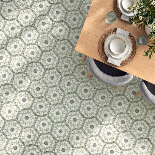 Dining room featuring Maroush Green 18.7x21.6cm Moroccan-style hexagon floor tiles, with intricate sage green, white and grey floral patterns, paired with a light oak dining table, upholstered chairs and natural woven accessories.