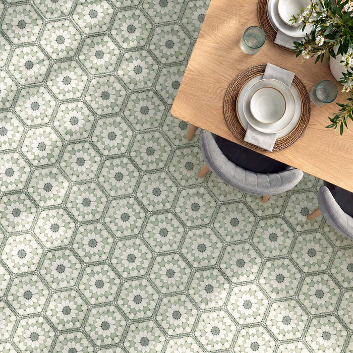 Dining room featuring Maroush Green 18.7x21.6cm Moroccan-style hexagon floor tiles, with intricate sage green, white and grey floral patterns, paired with a light oak dining table, upholstered chairs and natural woven accessories.
