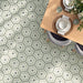 Dining room featuring Maroush Green 18.7x21.6cm Moroccan-style hexagon floor tiles, with intricate sage green, white and grey floral patterns, paired with a light oak dining table, upholstered chairs and natural woven accessories.