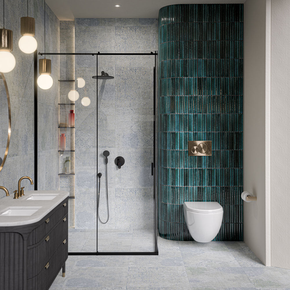 Bathroom featuring Mizu Blue Fluted Decor 6cm x 24cm gloss porcelain tiles across a curved feature wall, showcasing a rich blue-green finish and textured fluted surface, paired with soft blue patterned tiles and black shower fixtures.