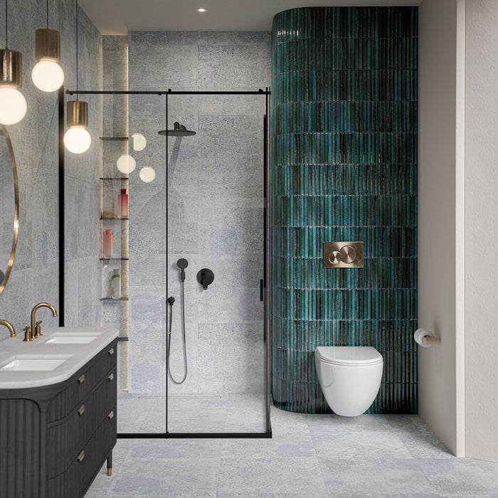 Bathroom featuring Mizu Blue Fluted Decor 6cm x 24cm gloss porcelain tiles across a curved feature wall, showcasing a rich blue-green finish and textured fluted surface, paired with soft blue patterned tiles and black shower fixtures.