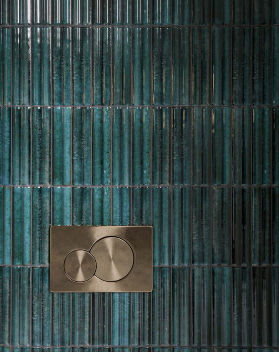 Close-up of Mizu Blue Fluted Decor 6cm x 24cm gloss porcelain tiles, showcasing a rich blue-green finish, tonal variation and textured fluted surface, paired with a brushed brass flush plate.