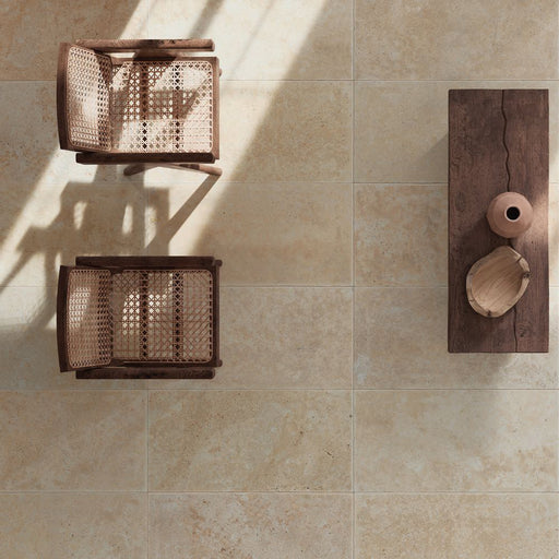 Monastry Flagstone XL Beige Travertine 50 × 100cm porcelain slabs, styled with warm wood furniture and woven textures to highlight soft tonal variation, a gently aged finish, and a natural travertine effect.