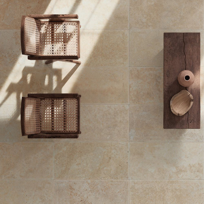 Monastry Flagstone XL Beige Travertine 50 × 100cm porcelain slabs, styled with warm wood furniture and woven textures to highlight soft tonal variation, a gently aged finish, and a natural travertine effect.